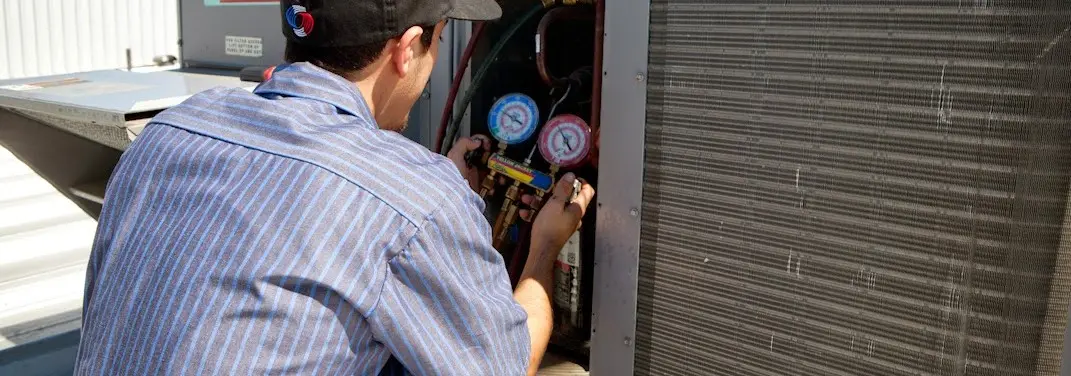 HVAC technician servicing a condenser unit in Wilson